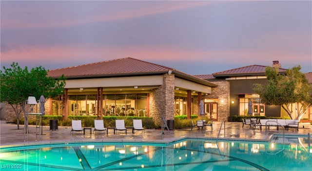 pool at dusk with central air condition unit and a patio area