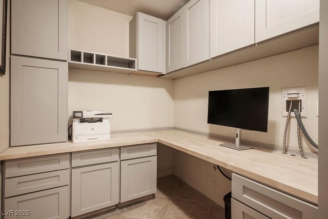 unfurnished office featuring built in desk and light tile patterned floors