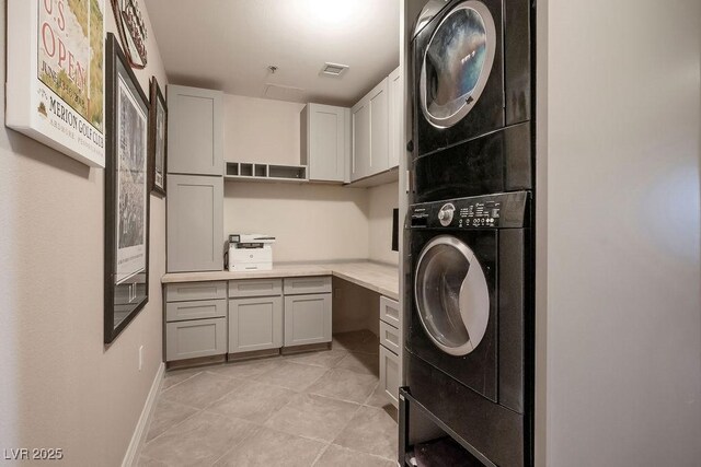 washroom with cabinets and stacked washer and dryer