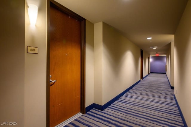 hall with dark colored carpet