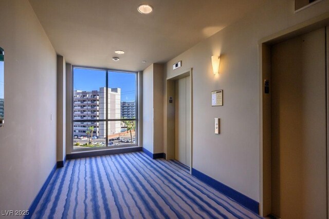 interior space with dark colored carpet, expansive windows, and elevator