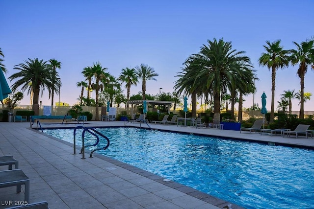 pool at dusk featuring a patio