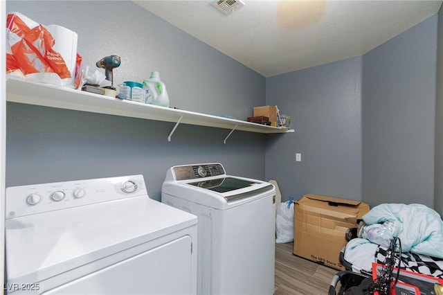 washroom featuring washing machine and dryer and light hardwood / wood-style floors