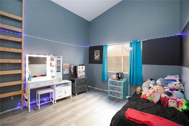 bedroom with high vaulted ceiling and light wood-type flooring