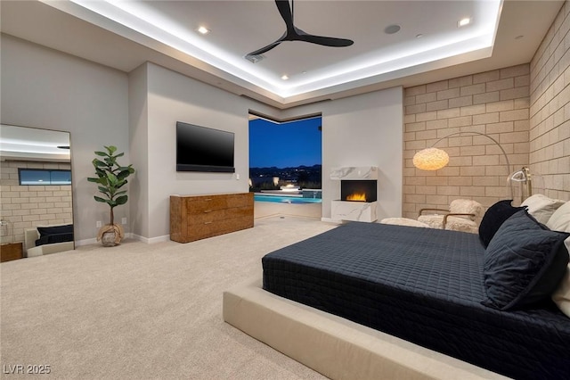 carpeted bedroom featuring ceiling fan and a raised ceiling