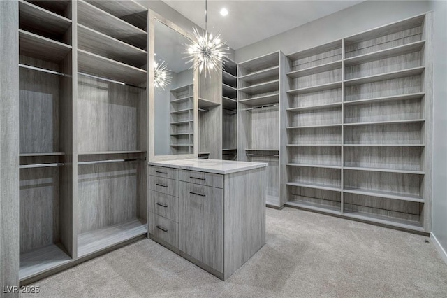 walk in closet with light colored carpet and an inviting chandelier