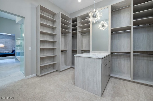 spacious closet with a notable chandelier and light carpet