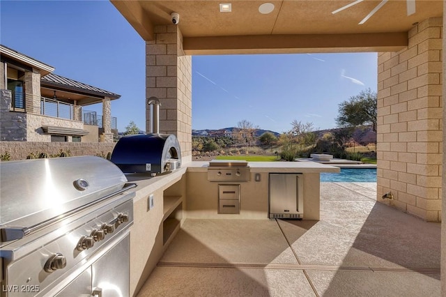 view of patio featuring area for grilling, ceiling fan, and an outdoor kitchen