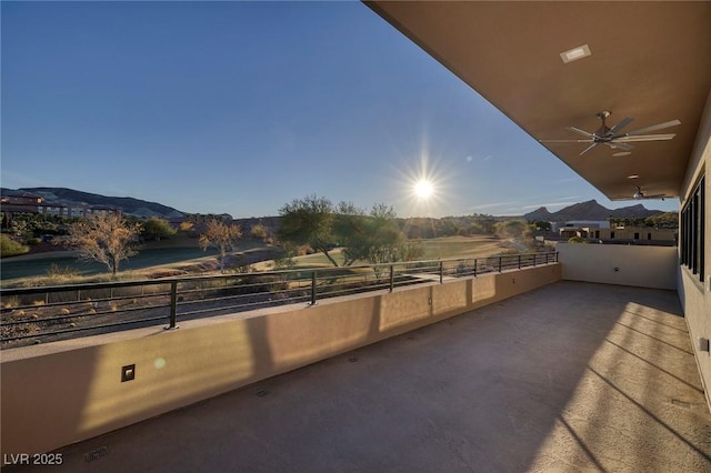 view of patio with ceiling fan, a balcony, and a mountain view