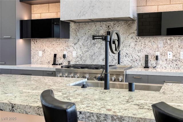 kitchen featuring gray cabinetry, decorative backsplash, and light stone countertops