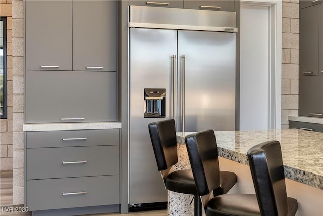 interior space featuring built in fridge, a kitchen breakfast bar, and gray cabinets