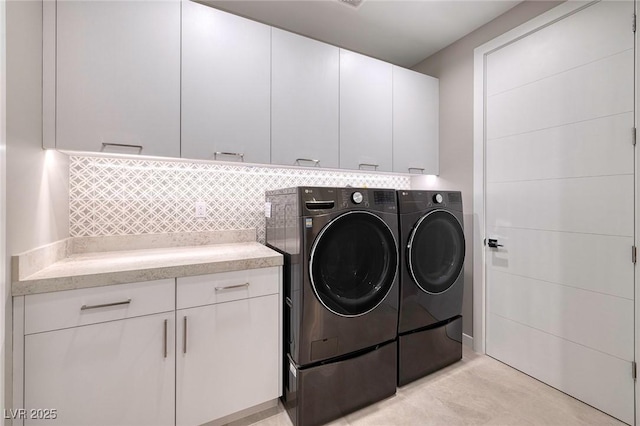 clothes washing area featuring cabinets and washer and dryer