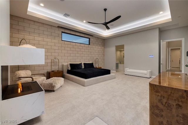 bedroom with carpet flooring, ceiling fan, a raised ceiling, and ensuite bathroom