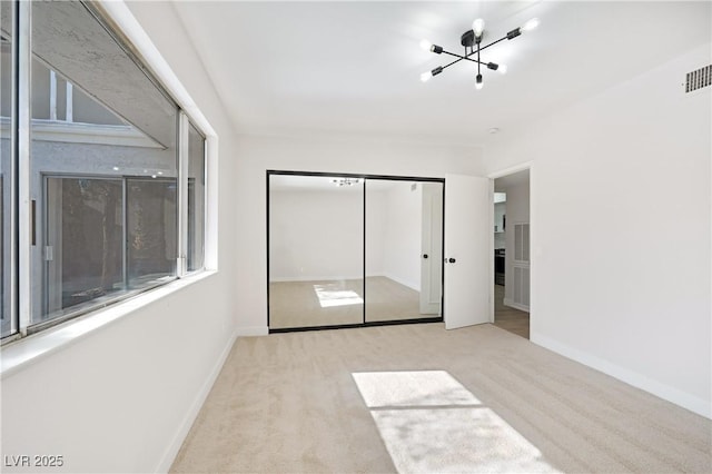 unfurnished bedroom with a chandelier, light colored carpet, and a closet