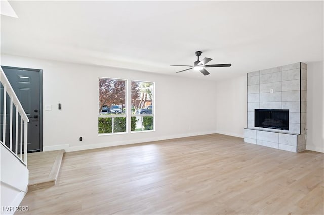 unfurnished living room with ceiling fan, a tile fireplace, and light hardwood / wood-style flooring