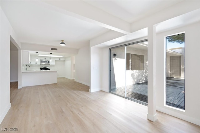 unfurnished living room featuring sink and light wood-type flooring