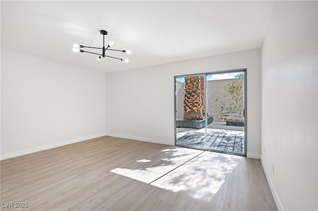 spare room featuring a chandelier and light wood-type flooring