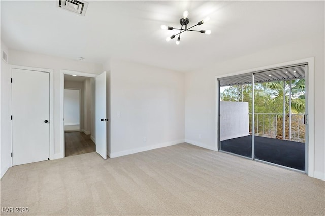 carpeted empty room with an inviting chandelier