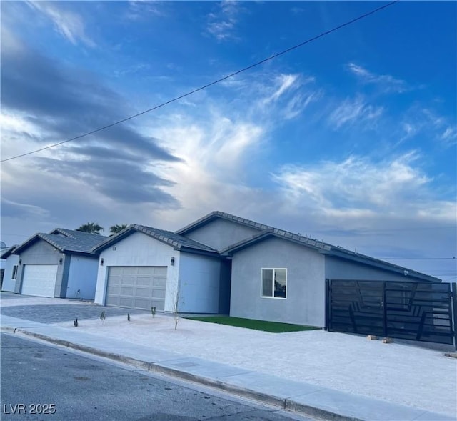 ranch-style house featuring concrete driveway, an attached garage, and stucco siding