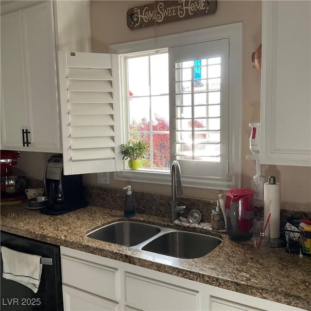 kitchen featuring black dishwasher, white cabinetry, and sink