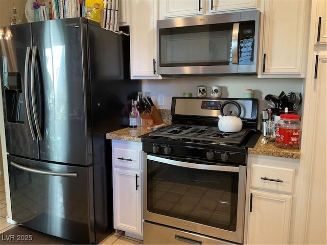 kitchen featuring white cabinets, appliances with stainless steel finishes, light tile patterned floors, and light stone counters