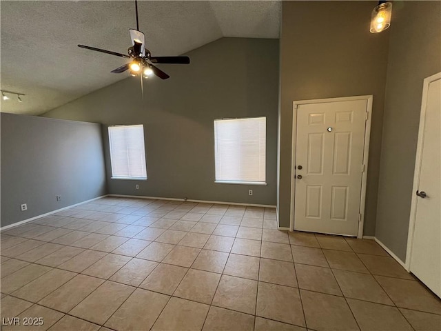 tiled empty room featuring ceiling fan, a textured ceiling, and vaulted ceiling