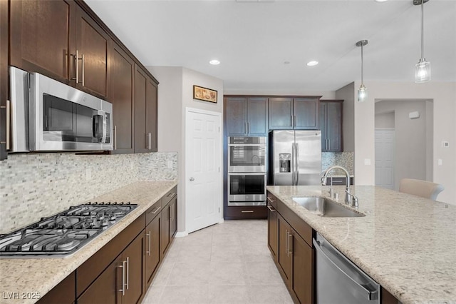 kitchen with stainless steel appliances, a sink, hanging light fixtures, dark brown cabinets, and tasteful backsplash