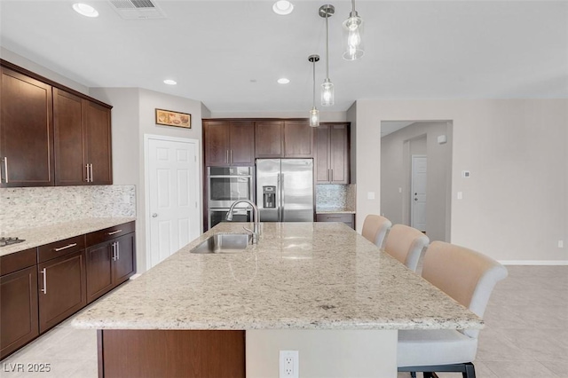 kitchen with a center island with sink, a breakfast bar area, stainless steel appliances, and a sink