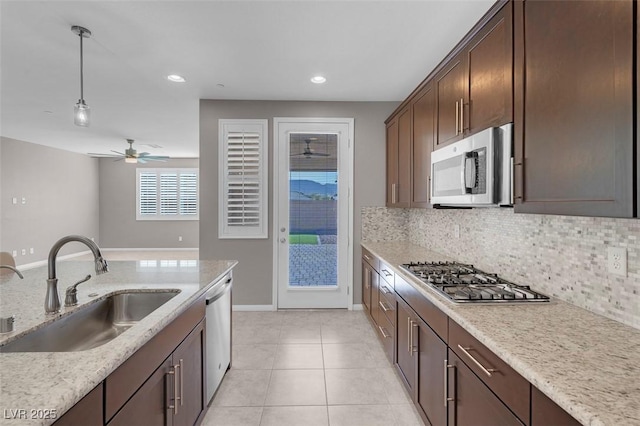 kitchen with sink, hanging light fixtures, light stone counters, decorative backsplash, and appliances with stainless steel finishes