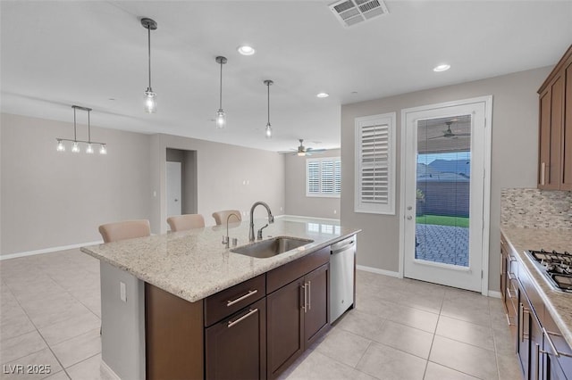 kitchen featuring visible vents, an island with sink, appliances with stainless steel finishes, decorative light fixtures, and a sink