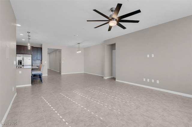 unfurnished living room with ceiling fan and baseboards