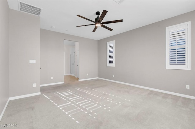 spare room with baseboards, visible vents, a ceiling fan, and light colored carpet