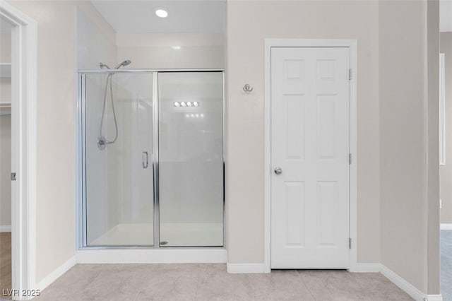 bathroom with a shower stall, baseboards, and tile patterned floors