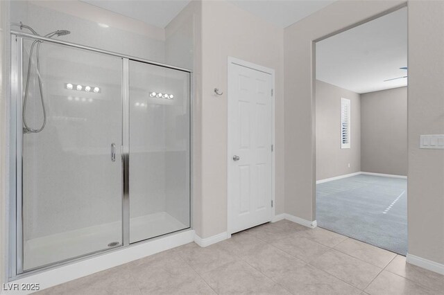 bathroom with a stall shower, tile patterned flooring, and baseboards