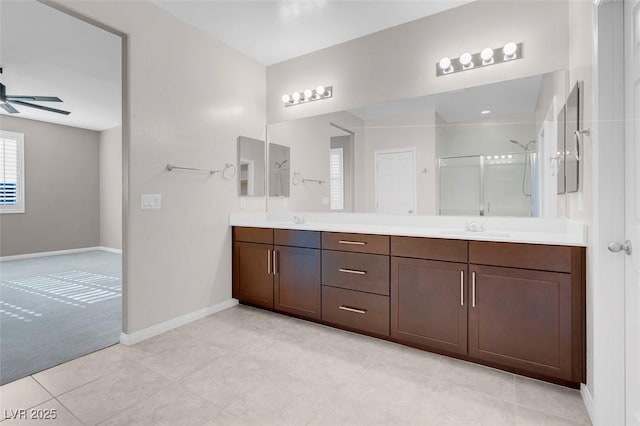 bathroom featuring double vanity, a stall shower, a ceiling fan, and a sink