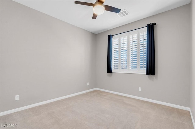 spare room featuring visible vents, baseboards, a ceiling fan, and light colored carpet