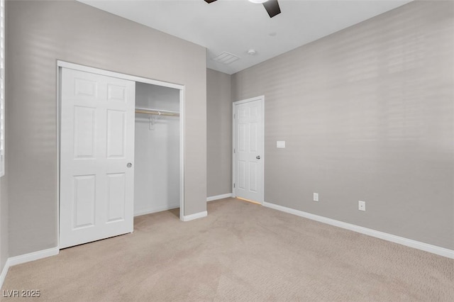 unfurnished bedroom featuring a ceiling fan, a closet, light colored carpet, and baseboards