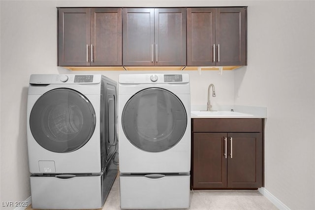 laundry area with independent washer and dryer, a sink, cabinet space, and baseboards