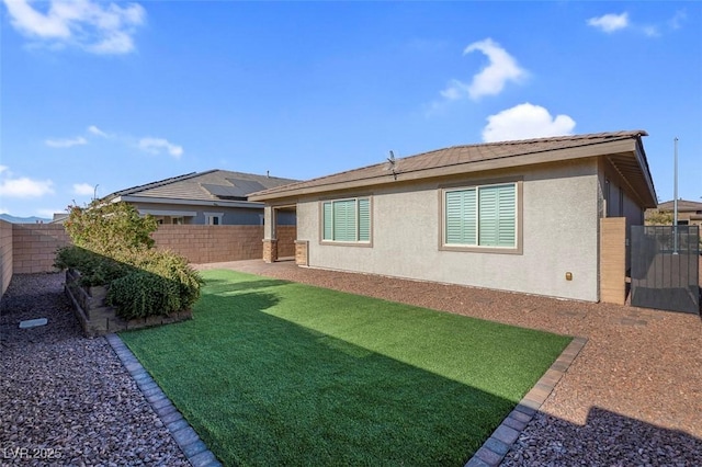 rear view of house featuring a yard, a fenced backyard, and stucco siding