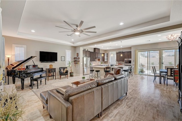 living room with a raised ceiling, ceiling fan, french doors, and light hardwood / wood-style floors