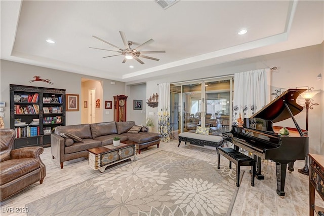 living room featuring a raised ceiling and ceiling fan