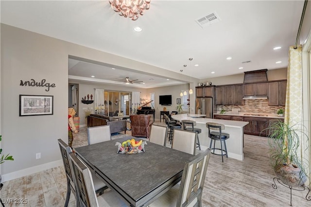 dining room featuring sink, ceiling fan with notable chandelier, and light wood-type flooring