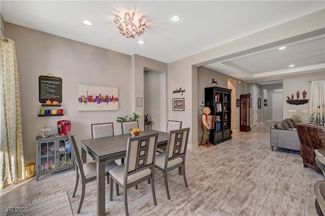 dining space with light hardwood / wood-style floors and an inviting chandelier