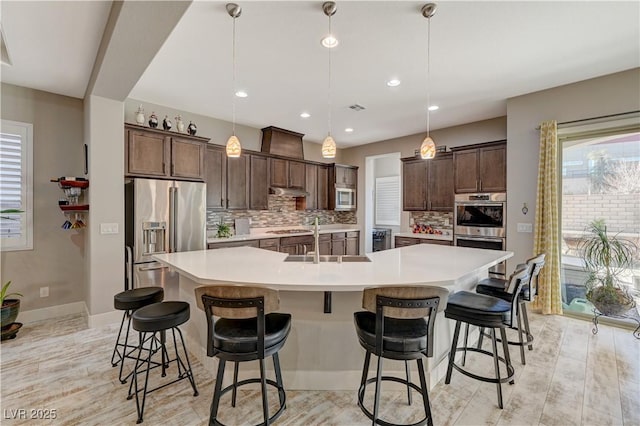 kitchen featuring sink, tasteful backsplash, a spacious island, decorative light fixtures, and appliances with stainless steel finishes