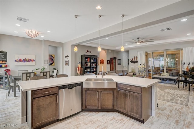 kitchen featuring a kitchen island with sink, sink, stainless steel dishwasher, ceiling fan, and decorative light fixtures