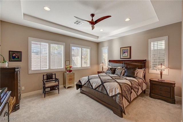 bedroom featuring a tray ceiling, ceiling fan, and light carpet