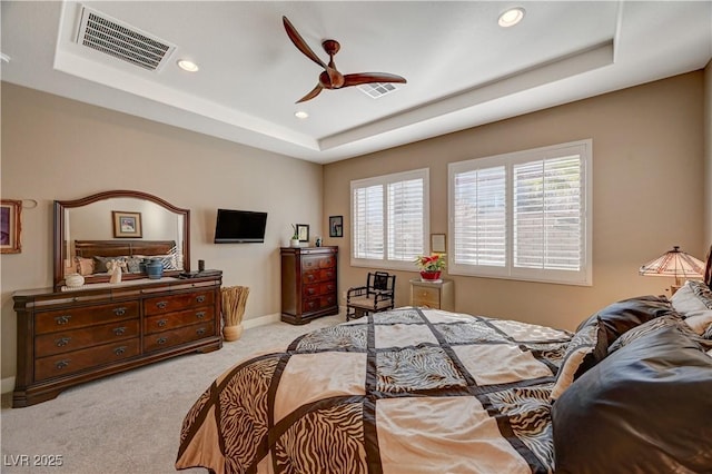 bedroom with light carpet, a tray ceiling, and ceiling fan