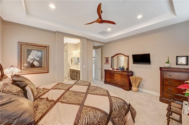 carpeted bedroom featuring ceiling fan, a raised ceiling, and connected bathroom