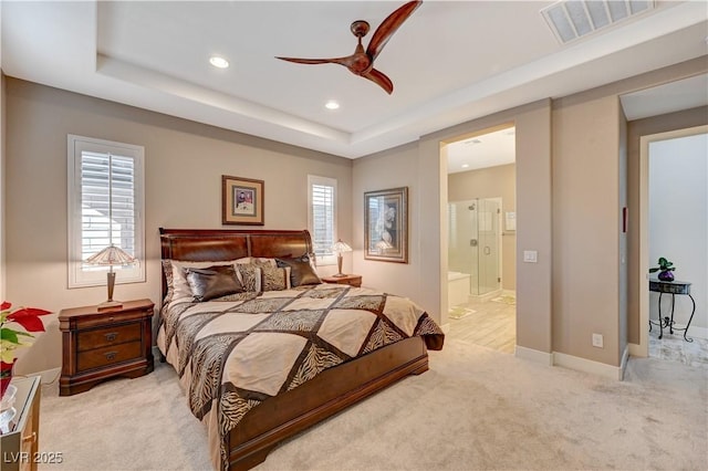 bedroom with connected bathroom, a tray ceiling, ceiling fan, and light colored carpet