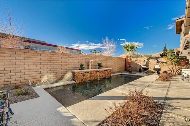 view of patio featuring pool water feature and a fenced in pool